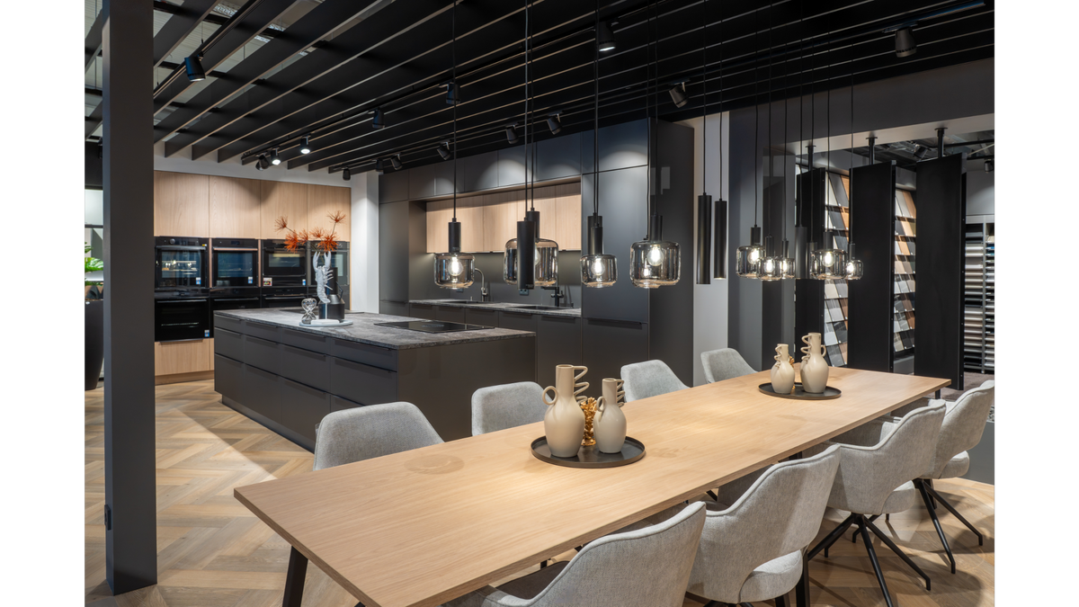 Moderne Showküche mit Kochinsel und langer Tafel für den Kochkurs